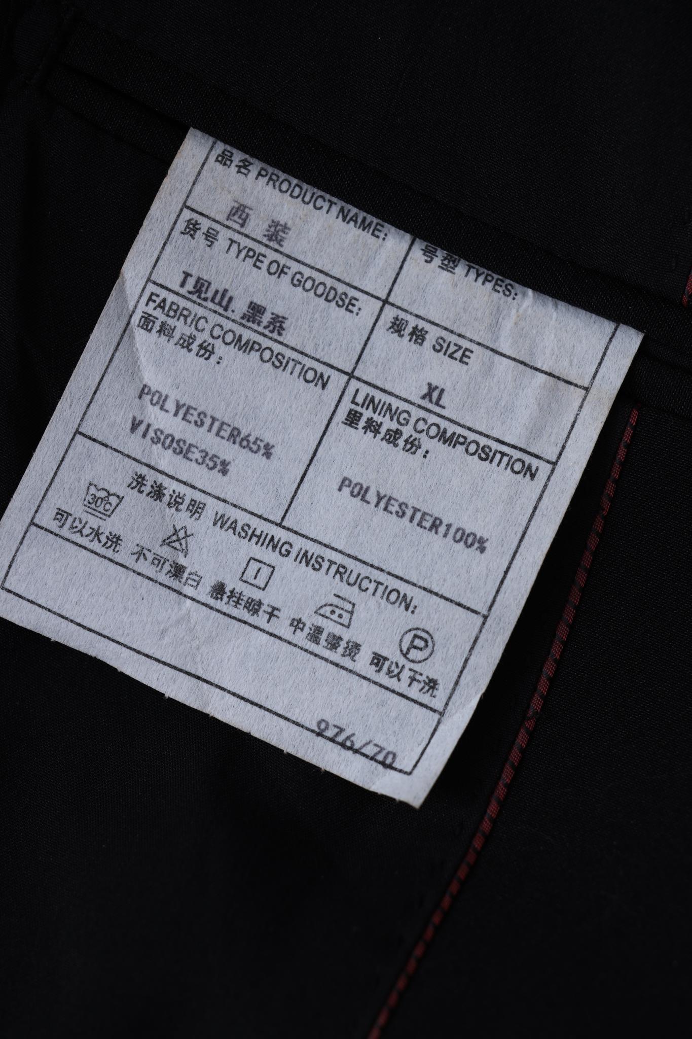 Close-up of a KIKI and JOJO tag for Kids Suit – Black 2-Piece Set (3-14 Years), Slim Fit, Wrinkle-Free, size XL, showing fabric/lining details and care instructions in English and Chinese.