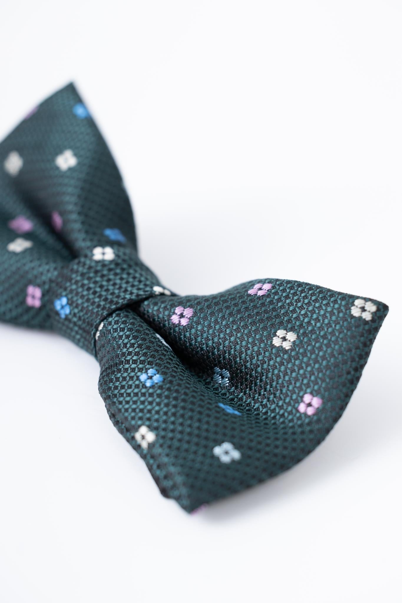 Close-up of the KIKI and JOJO Kids Bow Tie – Green – Pre-Tied Satin, adjustable for comfort, featuring small pink, white, and blue florals on premium fabric against a plain white background.