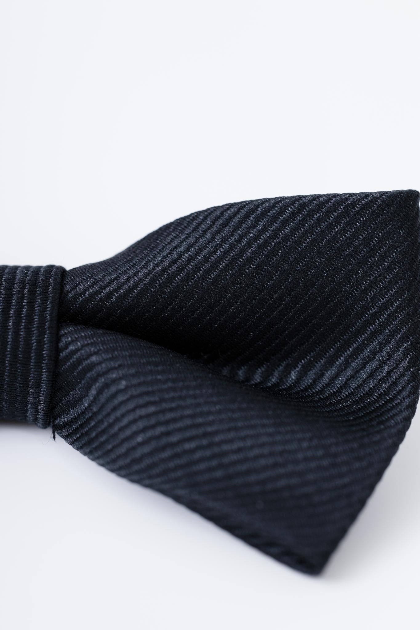 Close-up of the KIKI and JOJO Kids Bow Tie – Black – Pre-Tied Satin with adjustable fit, featuring a rich texture. Perfect accessory for kids dress shirts or tailored suits, shown against a light background.