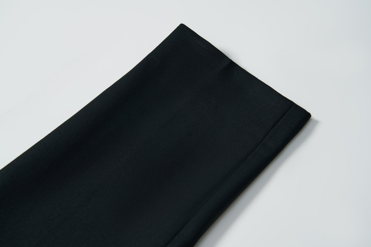 Close-up of KIKI and JOJO's Noir Bloom Suit Pants for boys, showing the straight-leg cut, hem, and fabric texture laid flat on a white surface—perfect formalwear.