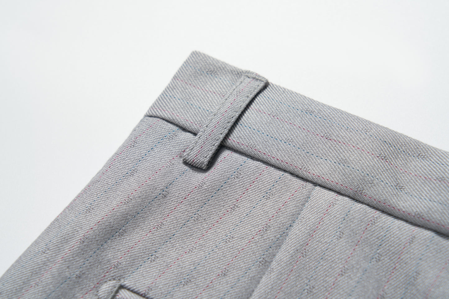 Close-up of the waistband and belt loop on KIKI and JOJO Silver Bloom Suit Pants, showcasing light gray pinstripes, textured fabric, and fine stitching details.