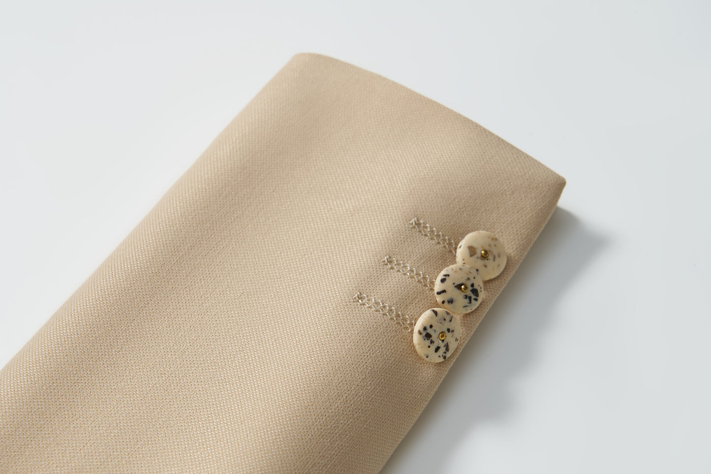 The Savoy Dune Suit Jacket by KIKI and JOJO features classic tailoring in khaki with three unique black and white detailed buttons on the sleeve, shown on a white background—ideal for boys’ formalwear.