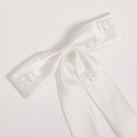 The Girls Hand-Beaded Pearl Satin Bow Hair Clip by KIKI and JOJO features embroidered patterns and beaded details on each loop and tail, making it a perfect flower girl accessory. Shown against a light plain background.