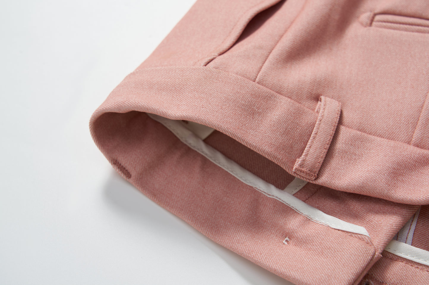 Close-up of the hem and waistband of KIKI and JOJO's Blush Reverie Suit Pants, featuring a belt loop, adjustable waistband, and inner white lining against a white background.
