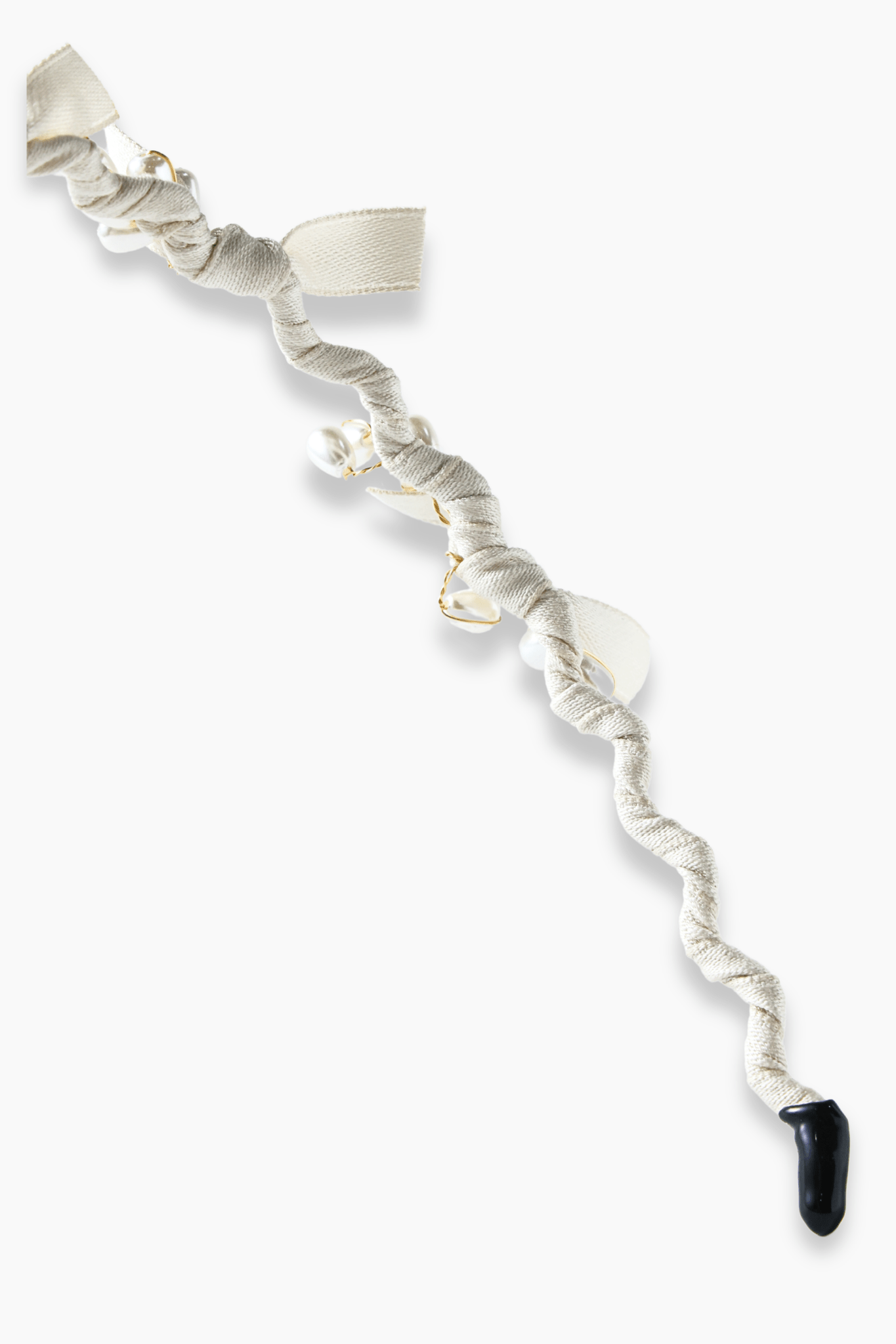 The KIKI and JOJO Girls Bow Hairband - Pearl features a twisted white fabric with bow details, pearl-like beads, and a black teardrop ornament at one end, shown on a white background.