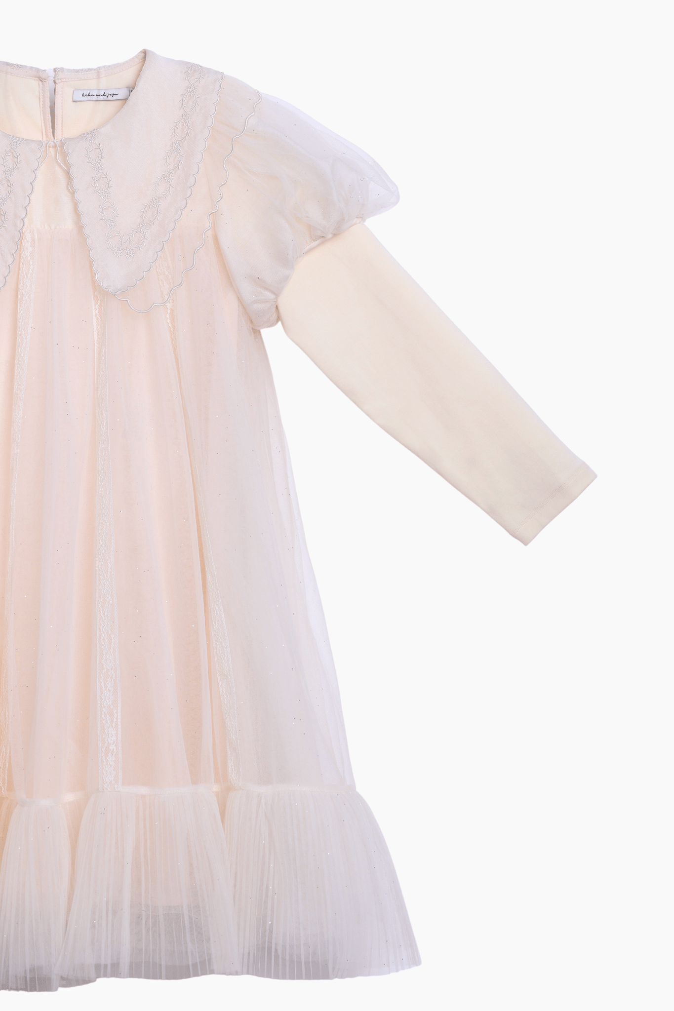 The KIKI and JOJO Girls Embroidered Satin Collar Sparkle Tulle Dress in beige/ivory features a long-sleeve faux two-piece design with a tulle overlay, embroidered satin collar, puffed shoulders, and a ruffled hem, shown on a white background.