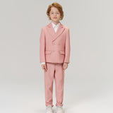 A young child with light brown hair faces forward, wearing KIKI and JOJO’s Blush Reverie Suit Pants with an adjustable waistband, a white shirt, and white sneakers against a plain light background.