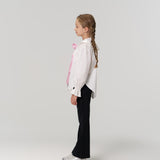 A young girl with braided hair, wearing a white shirt, KIKI and JOJO Echo Whisper Dress Pants with an elastic waistband, and silver shoes stands in profile against a plain light background.