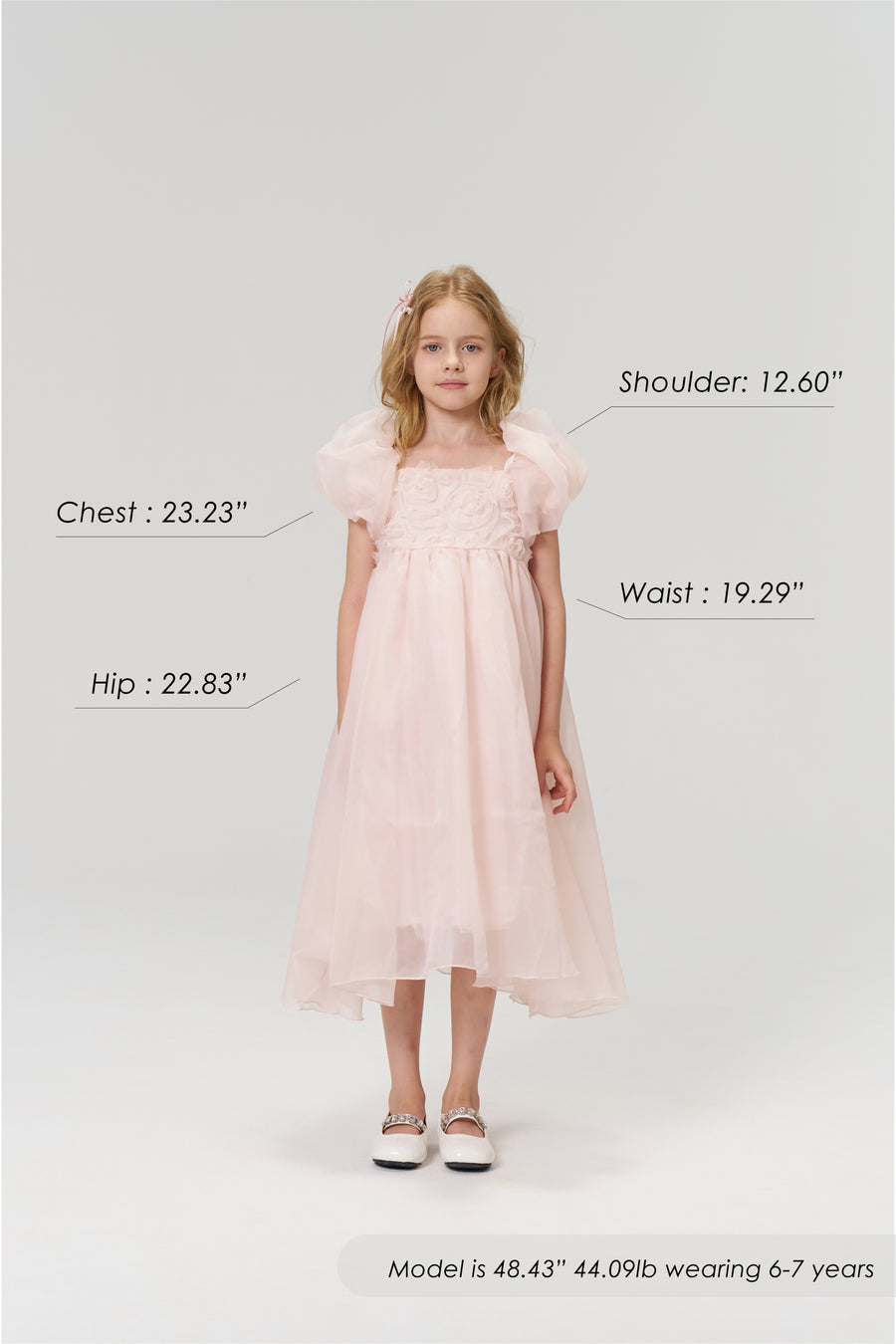 A young girl models the KIKI and JOJO Blush Whisper Dress, featuring puff sleeves in princess style; her chest, hip, shoulder, and waist measurements are shown, along with height, weight, and suitable age range.