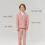 A young boy wears KIKI and JOJO Blush Reverie Suit Pants, posing forward to display the boys’ formal trousers with an adjustable waistband. Model’s size details are shown. Neutral gray background.