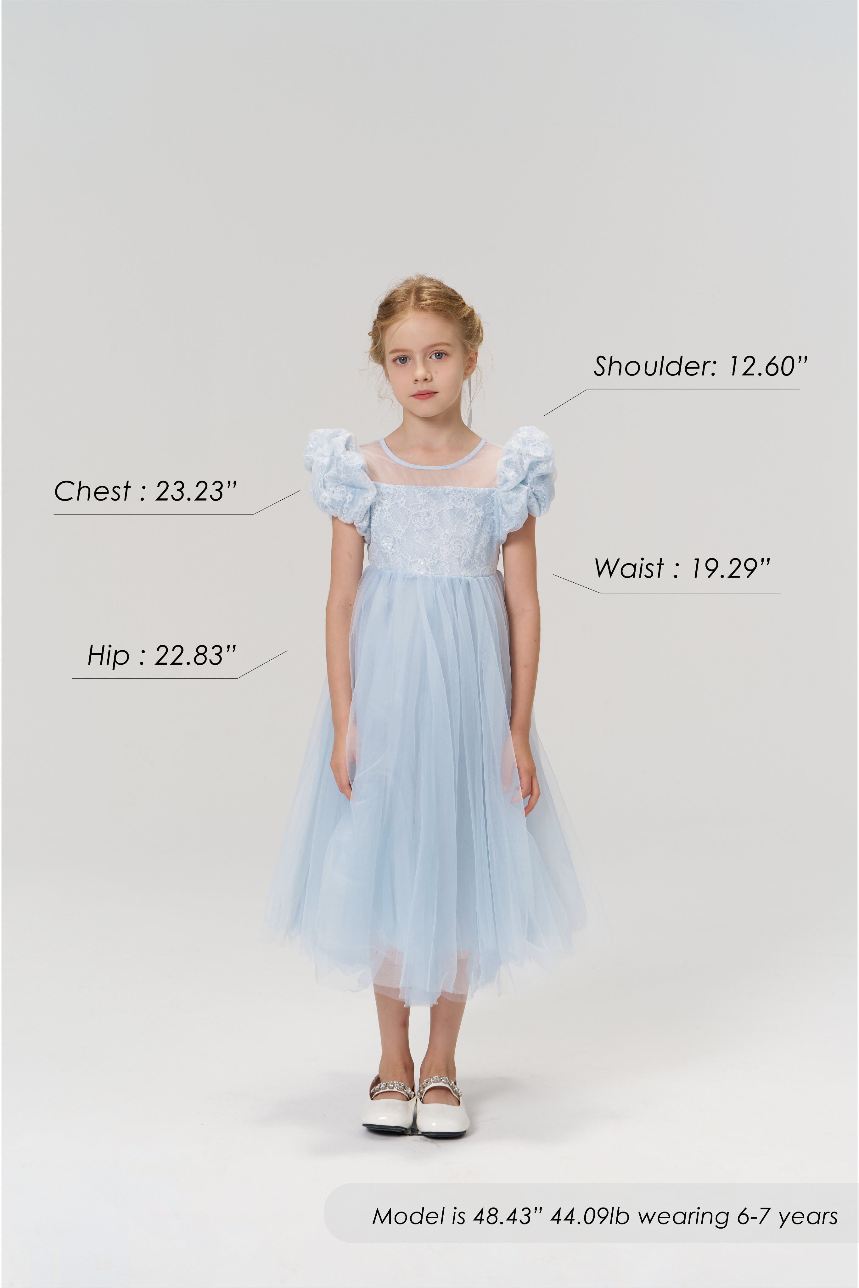 A young girl faces forward wearing the Sky Whisper Dress by KIKI and JOJO; her height, weight, age, and the dress's size measurements are displayed around her.
