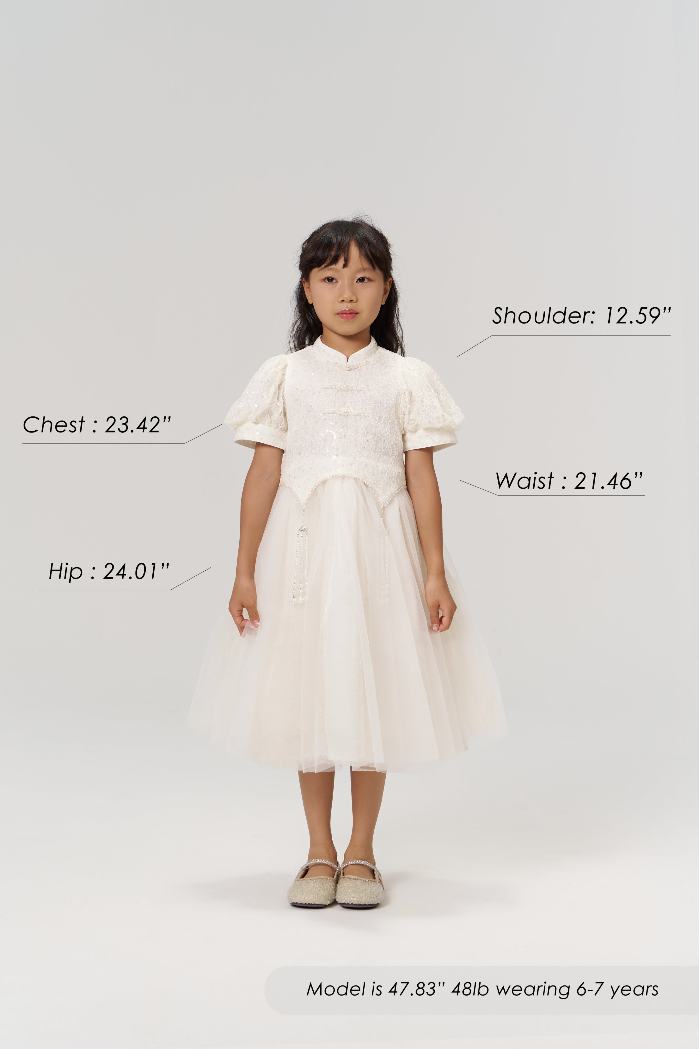 A young girl faces forward in the Orchid Whisper Dress by KIKI and JOJO with beige shoes; her height, weight, age, and body measurements are labeled around her on a plain light background.