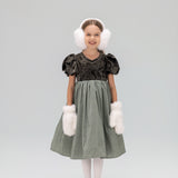 A young girl wears the KIKI and JOJO Girls Velvet Puff Sleeve Dress with Rhinestone Trim in forest green, paired with white earmuffs, fluffy mittens, tights, and gray shoes, smiling at the camera against a plain light background.