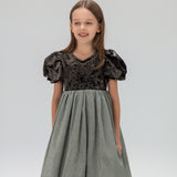A young girl stands against a plain light background wearing the KIKI and JOJO Girls Velvet Puff Sleeve Dress with Rhinestone Trim in forest green.