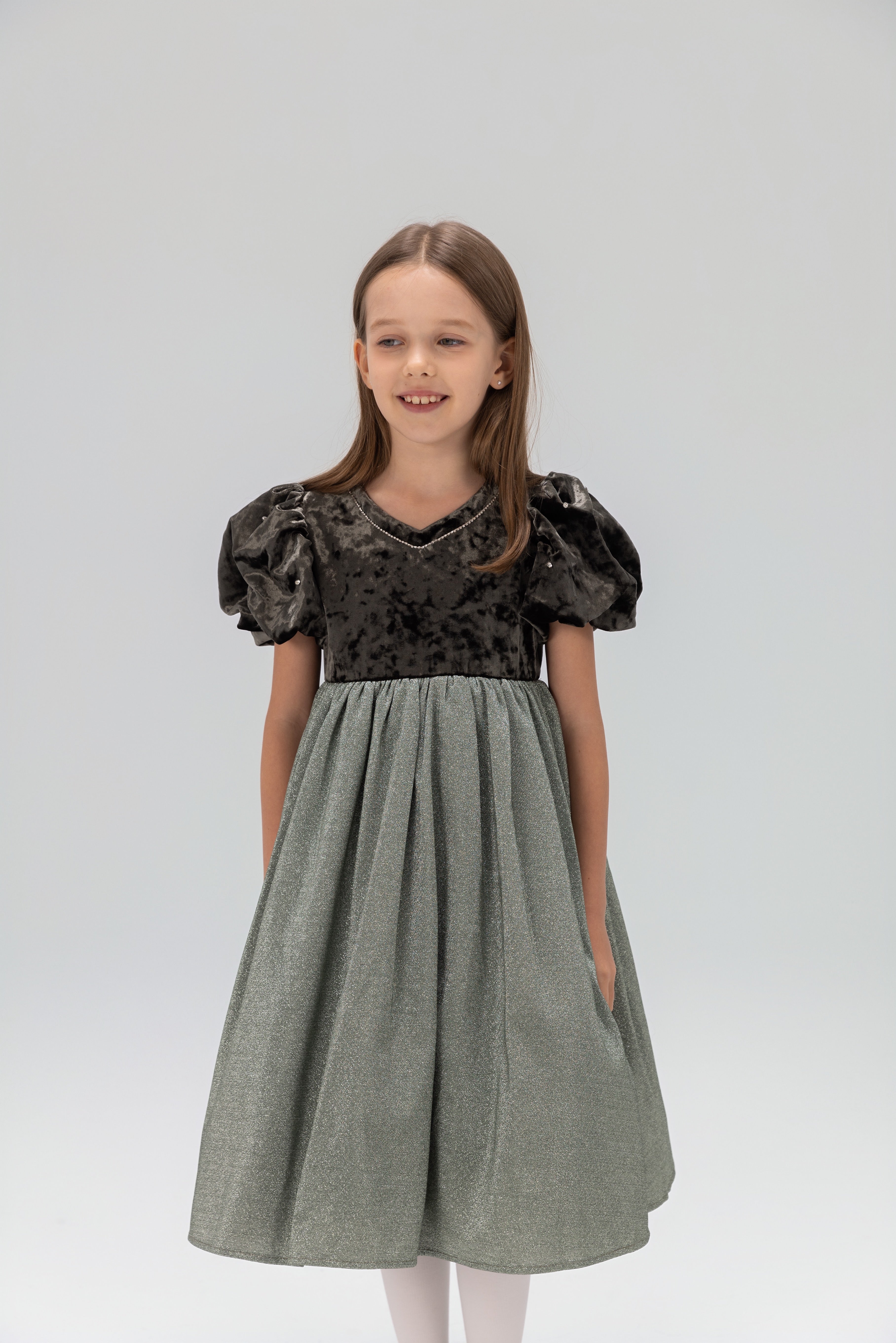A young girl stands against a plain light background wearing the KIKI and JOJO Girls Velvet Puff Sleeve Dress with Rhinestone Trim in forest green.