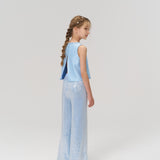 A young girl with braided hair stands facing away, wearing a light blue sleeveless top and KIKI and JOJO's Radiance Sequin Wide-leg Pants against a plain light background.
