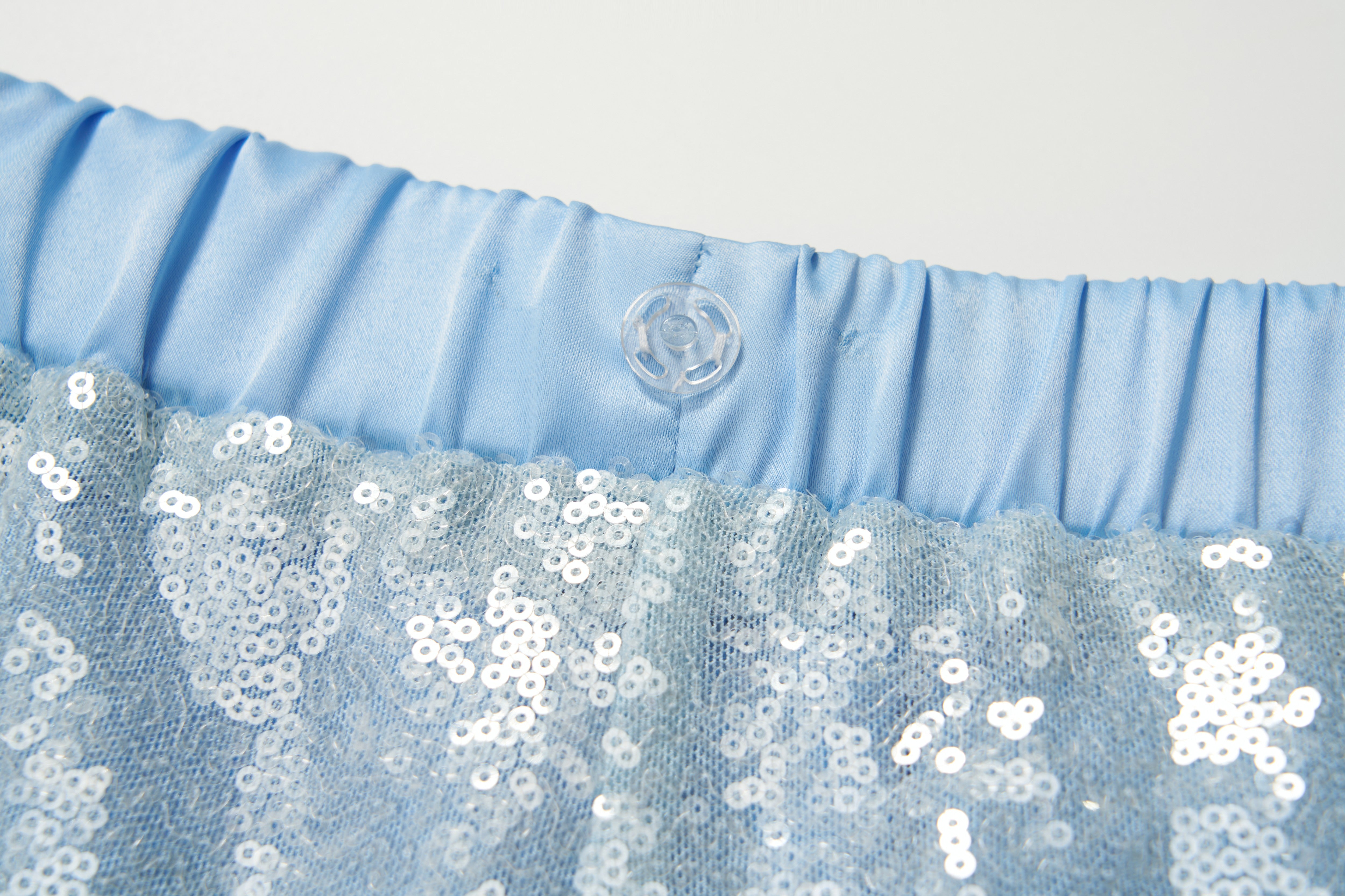 Close-up of the light blue elastic waistband with a clear button and sparkling sequin fabric on KIKI and JOJO’s Radiance Sequin Wide-leg Pants, showcasing their glamorous high-rise silhouette.
