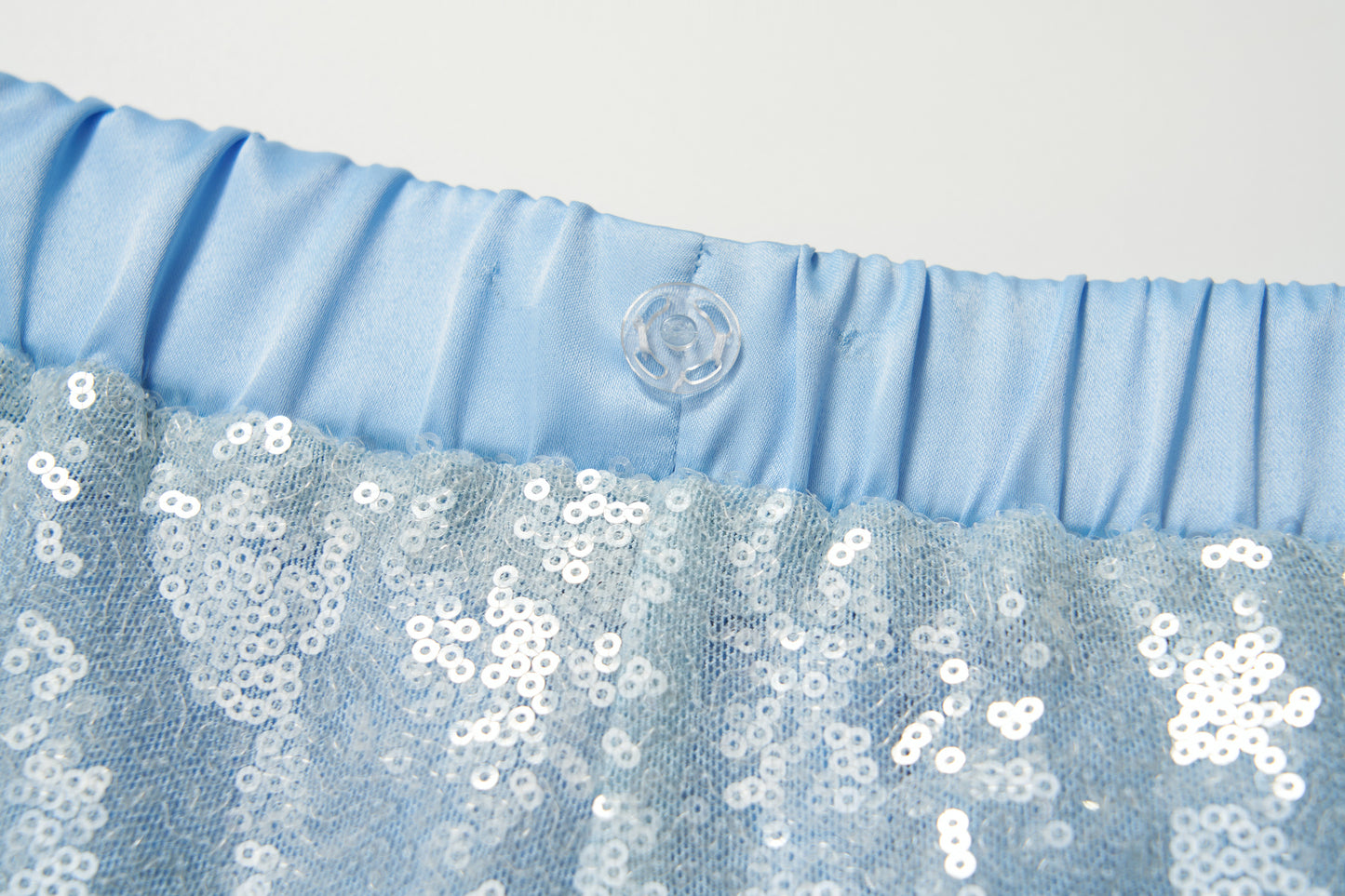 Close-up of the light blue elastic waistband with a clear button and sparkling sequin fabric on KIKI and JOJO’s Radiance Sequin Wide-leg Pants, showcasing their glamorous high-rise silhouette.