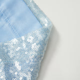 Close-up of light blue fabric embellished with shiny white sequins, reflecting the elegant detail of KIKI and JOJO's Radiance Sequin Wide-leg Pants, set against a plain white background.