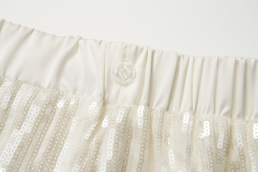 Close-up of an off-white elastic waistband with a transparent button, featured on the KIKI and JOJO Radiance Sequin Wide-Leg Pants with high-rise fit and white sequins.