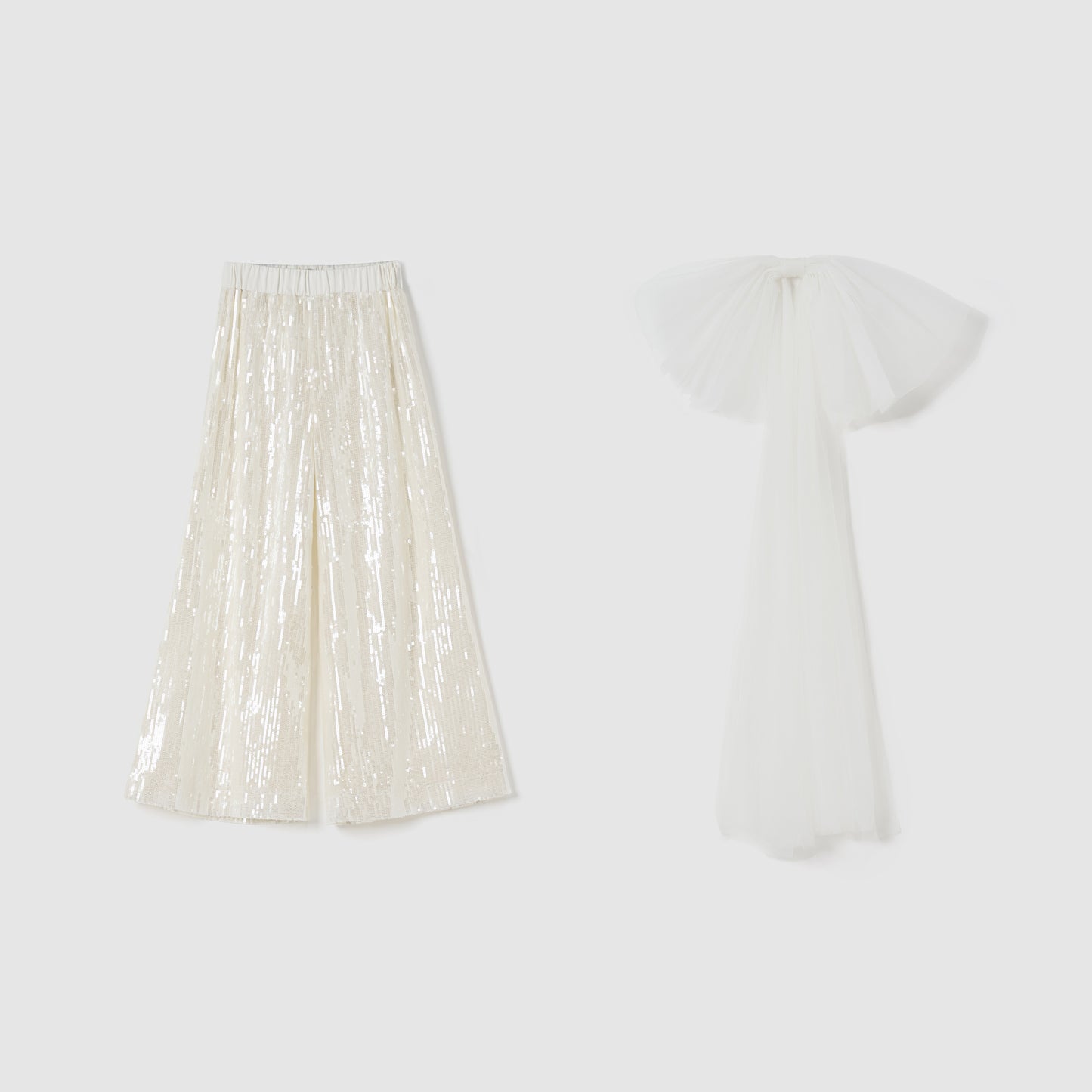 The Radiance Sequin Wide-Leg Pants by KIKI and JOJO, in shiny cream, are displayed beside a long white tulle garment with a detachable bow train on a plain background.