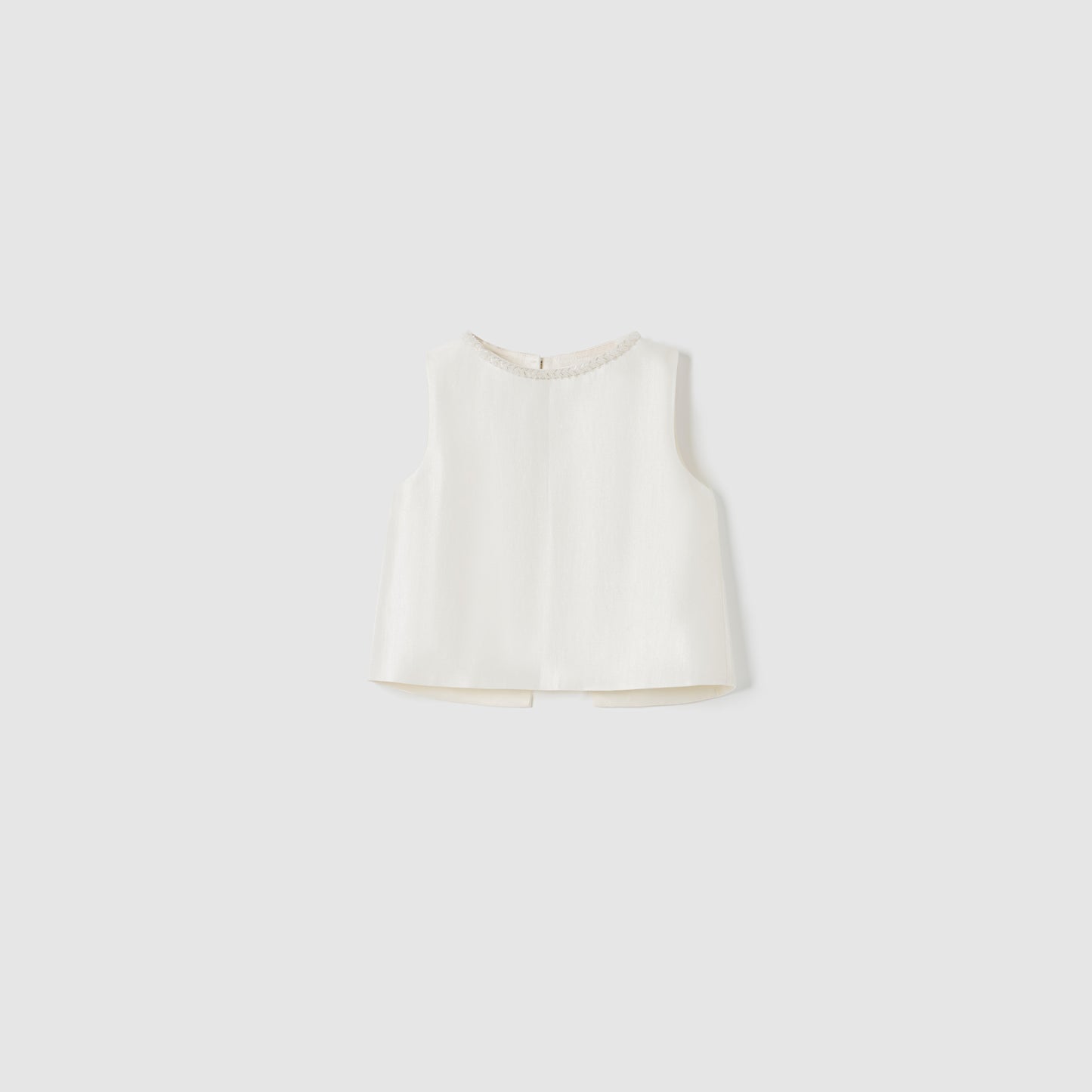 The Radiance Satin Crop Top by KIKI and JOJO is a sleeveless white satin crop top featuring a hand-beaded pearl neckline, shown on a plain light gray background.