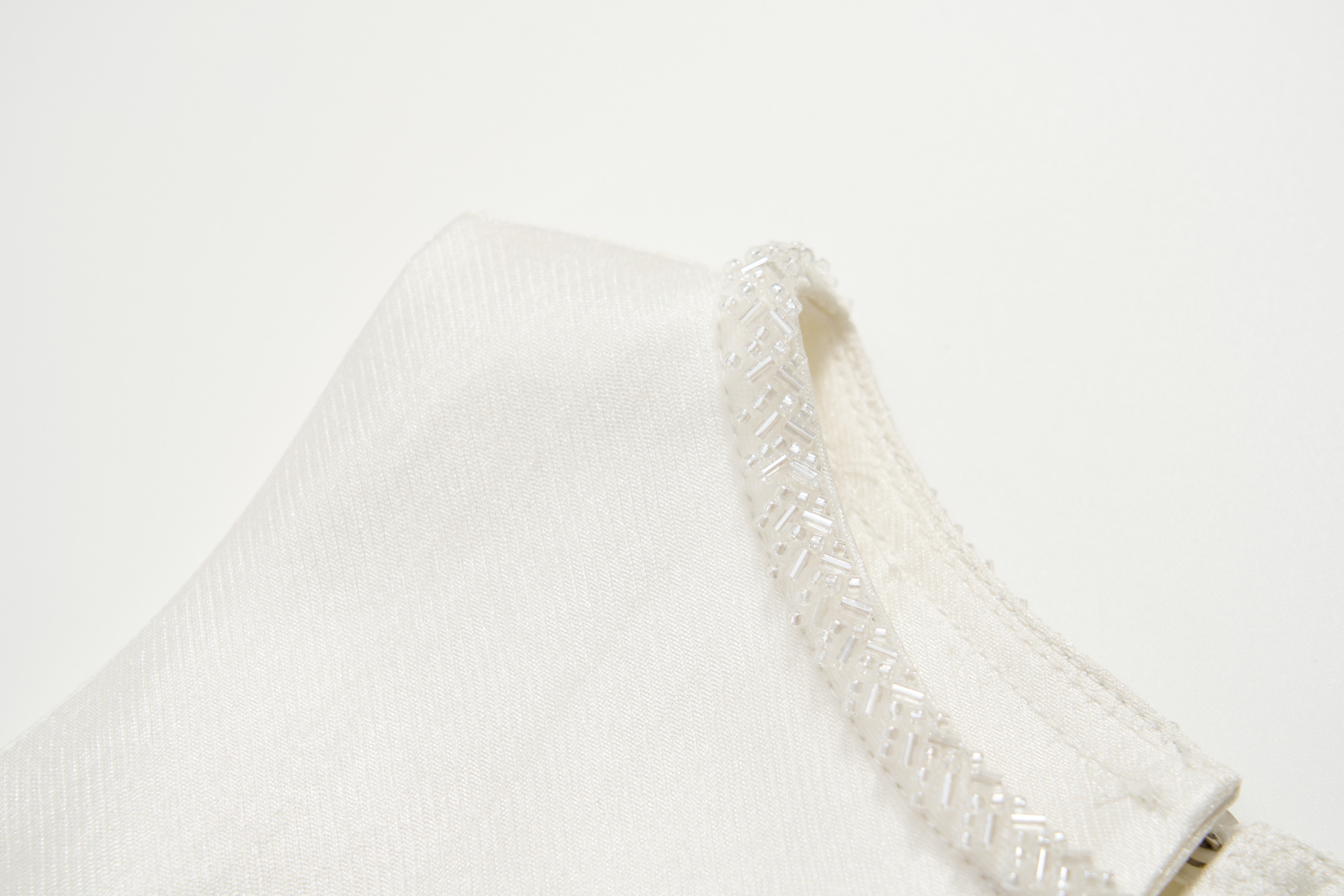 Close-up of the Radiance Satin Crop Top by KIKI and JOJO, featuring a hand-beaded pearl neckline, photographed against a plain white background.