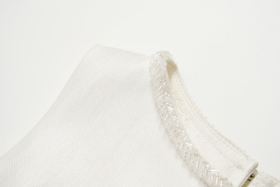 Close-up of the Radiance Satin Crop Top by KIKI and JOJO, featuring a hand-beaded pearl neckline, photographed against a plain white background.
