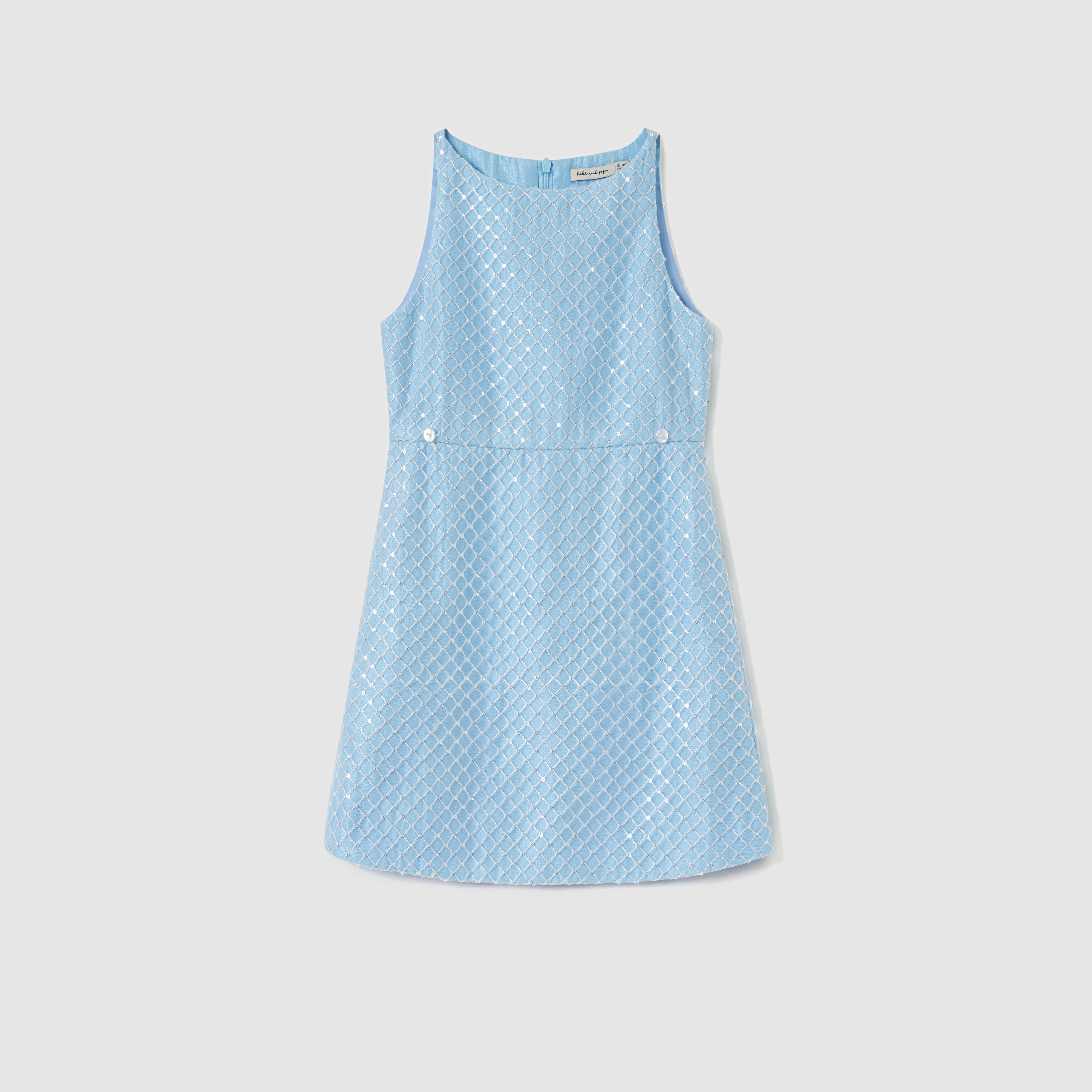 The KIKI and JOJO Radiance Sequin Overlay Dress is a sleeveless light blue formal dress, featuring a diamond-pattern texture, front buttons at the waist, and a back zipper, shown on a plain white background.