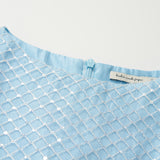 Close-up of the Radiance Sequin Overlay Dress by KIKI and JOJO, a light blue sleeveless formal dress featuring white embroidered geometric patterns, a back zipper, and a visible label inside the neckline.