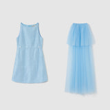 On a plain background: on the left, a sleeveless, patterned light blue A-line dress; on the right, KIKI and JOJO's Radiance Sequin Overlay Dress with layered sequin tulle and a fitted waist.