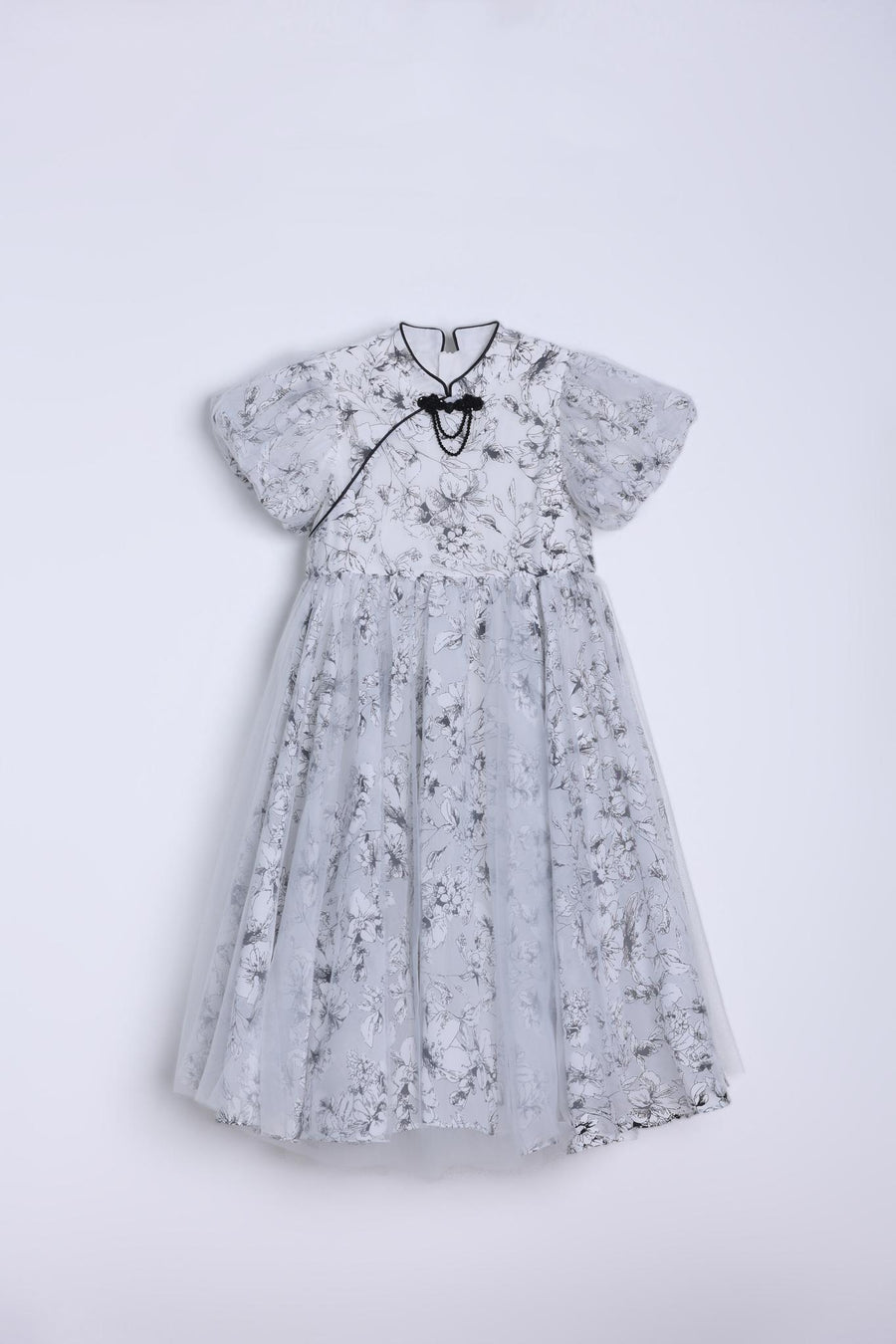 The KIKI and JOJO Girls Cheongsam Dress – Ethereal Blossom Puff Sleeve Tulle is a floor-length white dress with a delicate floral pattern and full tulle skirt, shown on a hanger against a plain white background.