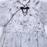 The KIKI and JOJO Girls Cheongsam Dress – Ethereal Blossom Puff Sleeve Tulle features a white base with black floral pattern, puffed short sleeves, tulle overlay skirt, mandarin collar, and a black decorative knot on the chest.
