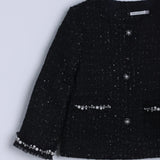 The Girls Tweed Jacket – Classic Black Pearl by KIKI and JOJO features long sleeves, front buttons, and vintage-inspired hand-beaded pearl details on the cuffs and pockets, shown against a light background.