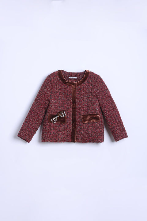 The KIKI and JOJO Girls Tweed Jacket – Burgundy Velvet Pearl features a red patterned tweed, brown velvet trim, long sleeves, two front pockets, and a small bow on the left pocket, shown on a white background.