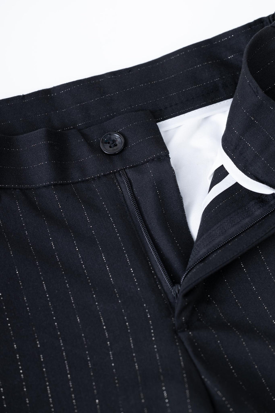 Close-up of KIKI and JOJO Kids Suit Pants in black, classic fit with wrinkle-free fabric, flat-front design, button closure, zipper, and white inner lining. Sizes 3-14 years.