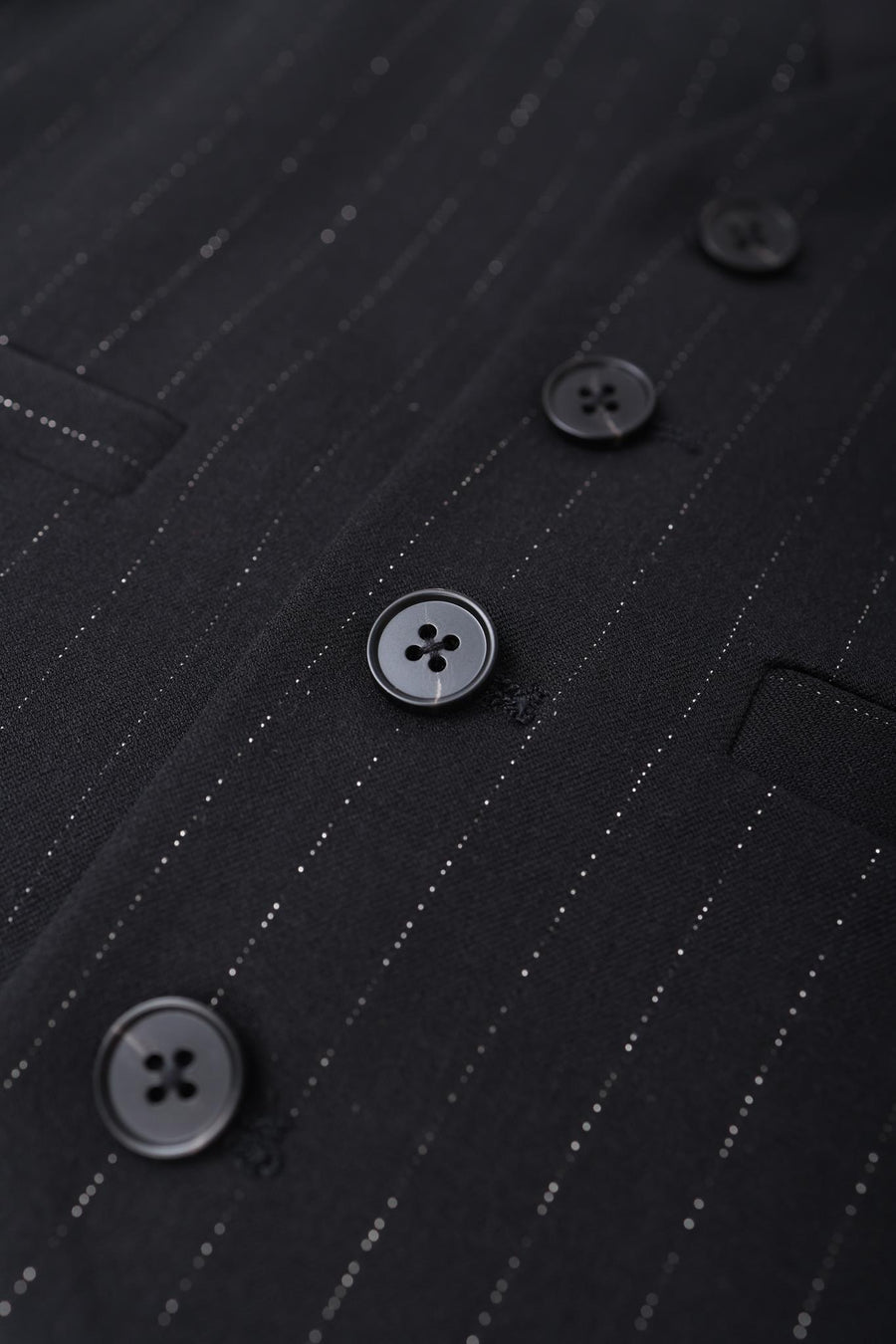 Close-up of KIKI and JOJO Kids Suit Vest in black, classic fit, wrinkle-free fabric, with four black buttons and two pockets. Suitable for ages 3-14.