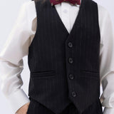 A child wears a white shirt, dark vest, maroon bow tie, and KIKI and JOJO Kids Suit Pants – Black (Classic Fit, Wrinkle-Free), with one hand in their pocket.