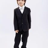 A young boy wears KIKI and JOJO Kids Suit Pants – Black (Classic Fit, Wrinkle-Free, 3-14 Years), paired with a white shirt and bow tie, standing against a plain white background.