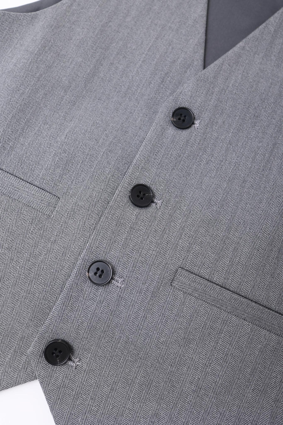 Close-up of the KIKI and JOJO Kids Suit Vest – Gray (3-14 Years), featuring a wrinkle-free, classic fit in herringbone fabric with four black buttons and two welt pockets for a tailored look.