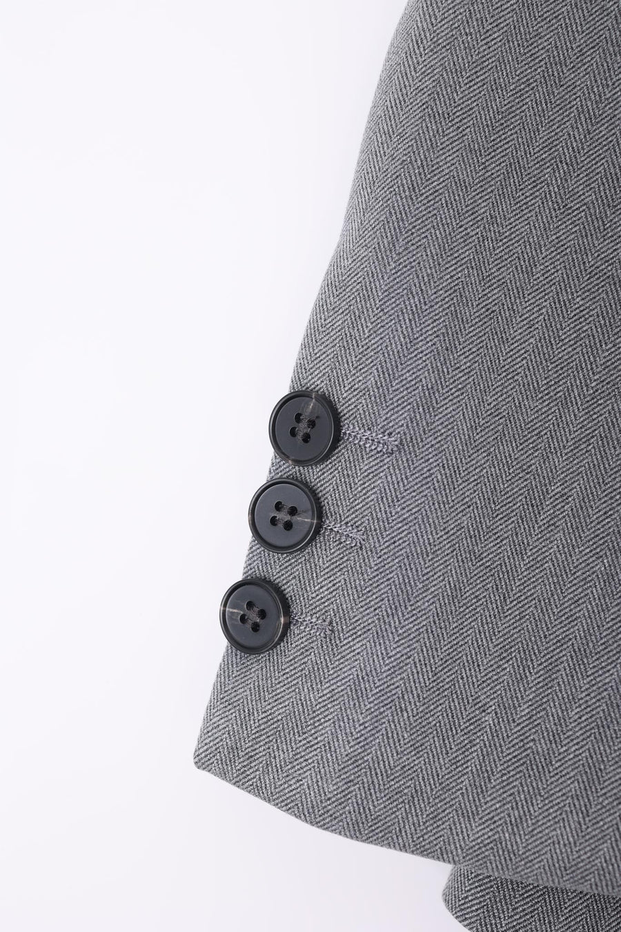 Close-up of the cuff on the KIKI and JOJO Kids Suit – Gray 3-Piece Set (3-14 Years), featuring three black buttons arranged in a row and made from wrinkle-free herringbone fabric.