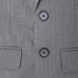Close-up of the KIKI and JOJO Kids Suit Jacket in gray, featuring a classic fit, wrinkle-free fabric, herringbone pattern, two black buttons, and two front pockets. Available for ages 3-14.