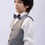 A young boy with dark hair wears a white shirt, grey vest, blue bow tie, and KIKI and JOJO Kids Suit Pants – Gray (Classic Fit, Wrinkle-Free) against a plain light background.