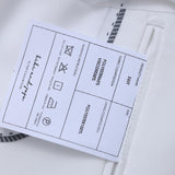 Close-up of the KIKI and JOJO Kids Suit Jacket – White (3-14 Years), Classic Fit, wrinkle-free, with a label showing care instructions, material details, and a signature for a timeless look.