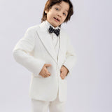 A young boy models the KIKI and JOJO Kids Suit Vest – White (3-14 Years), a classic fit, wrinkle-free vest, paired with a black polka dot bow tie. He stands confidently against a plain light background, hands on hips, looking at the camera.