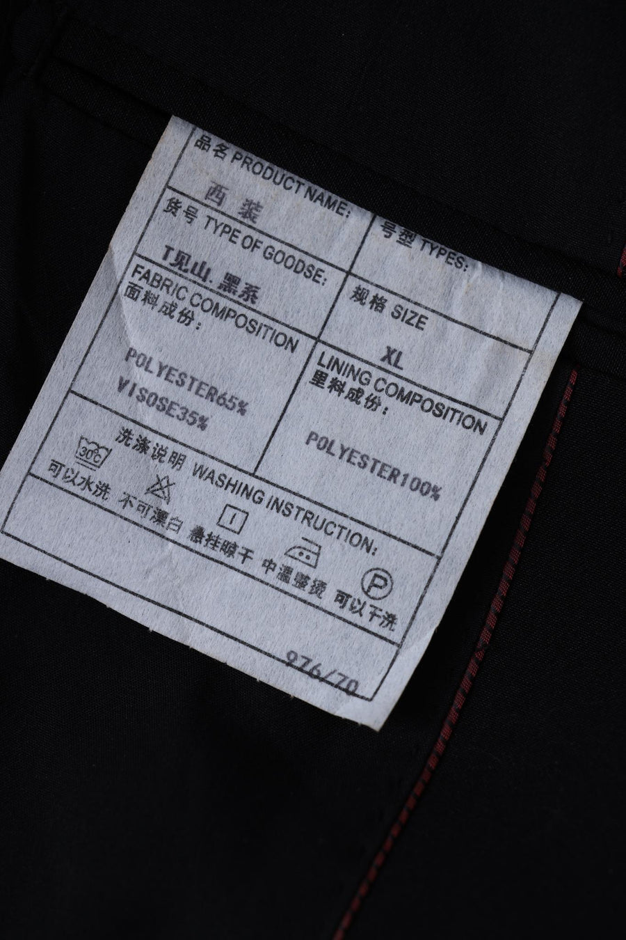 Close-up of a KIKI and JOJO tag for Kids Suit – Black 2-Piece Set (3-14 Years), Slim Fit, Wrinkle-Free, size XL, showing fabric/lining details and care instructions in English and Chinese.