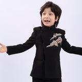 A young boy smiles with arms wide open, wearing the KIKI and JOJO Kids Suit Jacket – Black (3-14 Years), a slim-fit, wrinkle-free jacket, standing against a plain background.