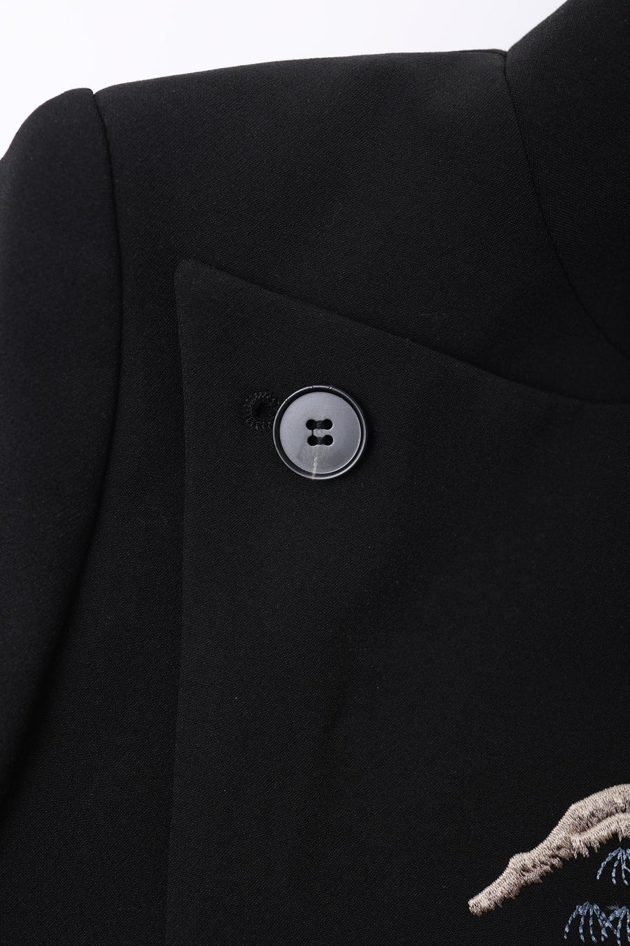 Close-up of the KIKI and JOJO Kids Suit – Black 2-Piece Set, slim fit with a Mandarin collar, round black button, and partial embroidered detail on the lower right side. For ages 3-14; wrinkle-free fabric.