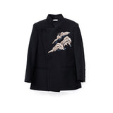 The KIKI and JOJO Kids Suit Jacket in black (ages 3-14) is a slim-fit, wrinkle-free blazer with a classic Mandarin collar and an asymmetrical front featuring wave-like embroidery on the left chest.