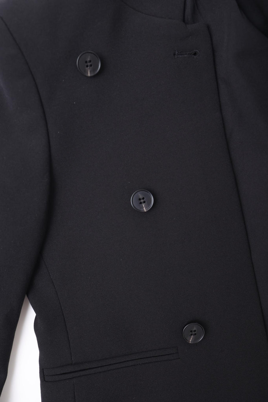 Close-up of the KIKI and JOJO Kids Suit Jacket in black, a wrinkle-free, slim-fit design for ages 3-14, featuring four black buttons and front pocket detail.